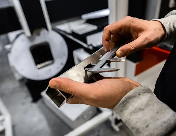 Engineer inspecting a formed sheet-metal part for dimensional accuracy