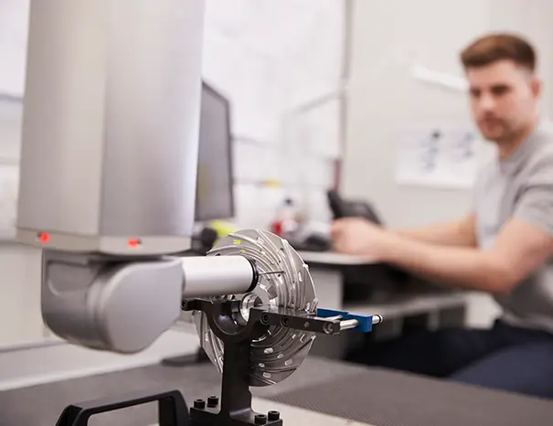 Quality engineer inspecting brake component dimensions on a CMM