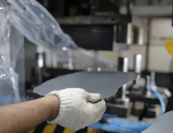 Hydraulic press forming a sheet-metal automotive bracket on a factory floor