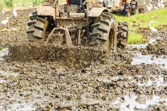 Tractor working in a wet field, showing the duty conditions its sheet metal must withstand